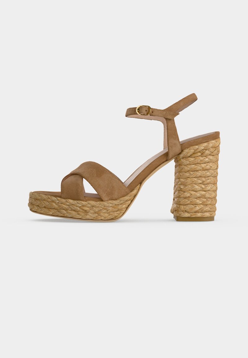 Sandale à plateforme en daim marron avec talon bloc recouvert de corde tressée et bride de cheville avec boucle dorée sur fond blanc.