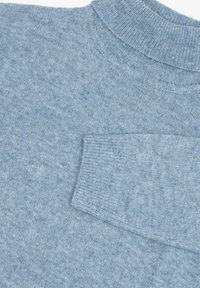Suéter de punto azul claro con un cuello acanalado y un bolsillo en el pecho. La tela tiene un aspecto texturizado con un acabado suave.