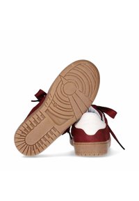 Un paio di sneakers rosse e bianche con suole in gomma, una scarpa mostra il motivo della suola sul fondo.