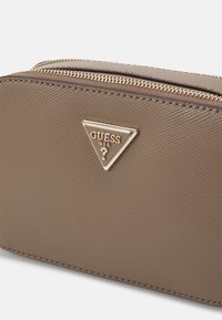 Borsa in materiale sintetico marrone con texture, caratterizzata da un logo triangolare in tonalità oro e un dettaglio con zip a vista lungo la parte superiore.