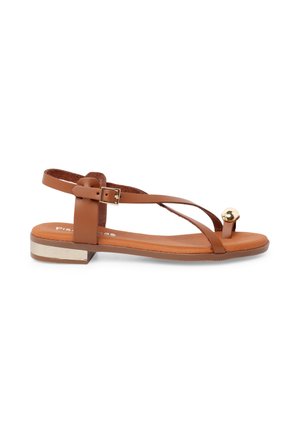 Brun flad sandal med tynde stropper, ankelspænde, gyldent accent på tåloopen og en lav hæl med en metallisk gylden detalje.