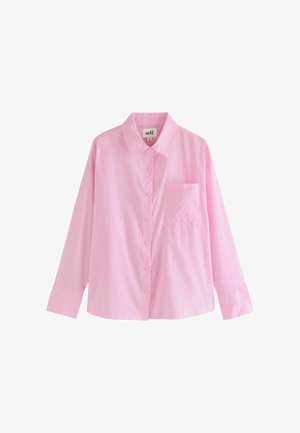 Vaaleanpunainen pitkähihaisen napillinen pusero, joka on valmistettu puuvillasta. Siinä on kauluspainike ja vasemmassa rintataskussa hienovarainen logo. Sileä tekstuuri.