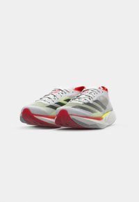 Chaussures de running légères avec une tige en maille grise et rouge, comportant des rayures noires et une semelle de couleur vive avec une finition texturée.