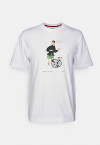 Osoba držící helmu s složeným kolem, na přední části bílého trička je napsáno "Připraven?"