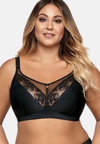 Soutien-gorge noir avec un panneau en dentelle transparente à motifs floraux, des bretelles réglables, un accent décoratif au centre et une texture lisse.