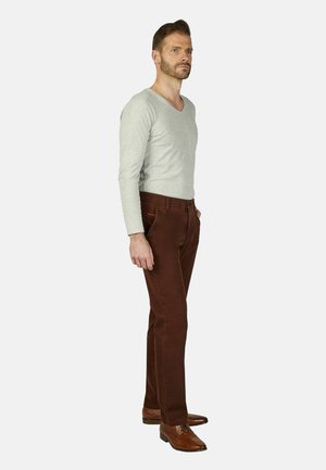 Grijze langmouw V-hals shirt gecombineerd met een bruine corduroy broek en bruine leren schoenen, weergegeven in een zijprofiel.