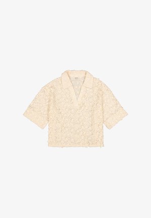 Blusa corta de encaje en color blanco roto, con cuello con solapas, patrón floral y un ajuste holgado con bordes deshilachados.