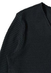 Chemise noire à manches longues avec un motif gaufré texturé et un col en V, présentée à plat sur un fond blanc.