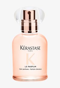 Kérastase Paris Le Parfum, perfume capilar en una botella de vidrio transparente con una tapa redondeada y transparente. Líquido rosa visible, con texto en plata y negro.