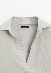 Chemise beige clair à col avec de fines rayures verticales et un col ouvert, featuring une étiquette noire Massimo Dutti à l'intérieur du col.