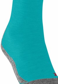 Türkisfarbener Sportsocken mit gerippter Textur, versehen mit einer grauen Spitze und Ferse. Der Socken ist mit einem kleinen roten Logo nahe der Bündchenkante verziert.