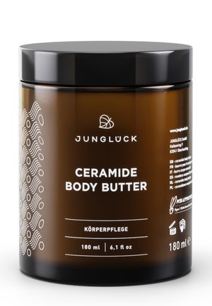 Braunes Glasgefäß der Junglück Ceramide Body Butter mit schwarzem Deckel, 180 ml, mit Etikett zur Hautpflege, zeigt Markenlogo und Produktdetails.