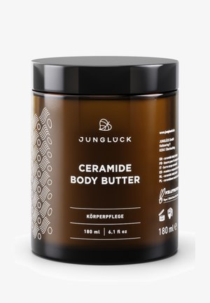 Braunes Glasgefäß der Junglück Ceramide Body Butter mit schwarzem Deckel, 180 ml, mit Etikett zur Hautpflege, zeigt Markenlogo und Produktdetails.
