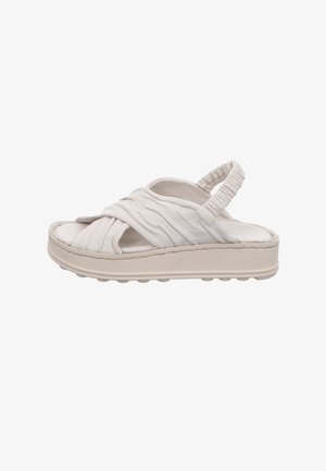 White sandal featuring a soft, textured upper with pleated straps, a cushioned footbed, and a thick, light-colored rubber sole.