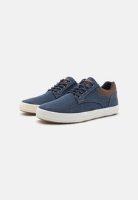 Navy canvas sneakers with brown leather accents, round toe, and white rubber sole; features laces and stitched detailing.