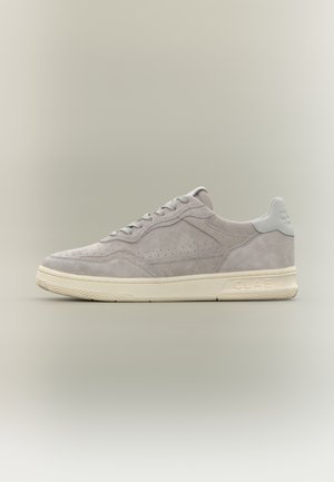 Pantof sport din piele întoarsă gri deschis cu talpă albă, panouri laterale perforate, șireturi și logo CLAE pe talpă și pe eticheta de pe călcâi.
