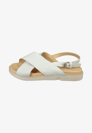 White sandal featuring crosshatched straps, a beige footbed, and an adjustable ankle strap. Flat sole with a slight heel.