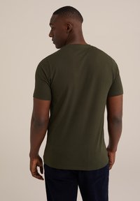 Zelené tričko s krátkým rukávem vyrobené z bavlny s kulatým výstřihem. Záda mají hladkou texturu a švy, řezaný střih.