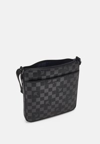 Borsa a scacchi nera realizzata in materiale sintetico testurizzato, con chiusura a zip, tracolla regolabile, tasca frontale e dettagli con logo.