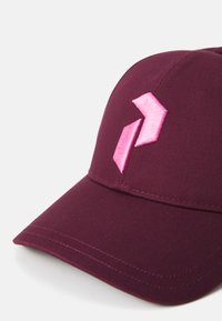 Mörkröd baseballkeps med böjd skärm och rosa broderad logotyp. Har texturerad tyg och synliga sömdetaljer.