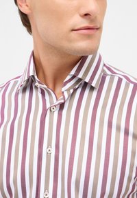 Camicia a righe con righe verticali in bordeaux, beige e bianco, colletto button-down e bottoni bianchi con cuciture decorative.