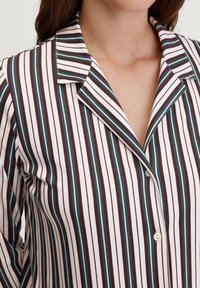 Gestreepte pyjamajack met smalle verticale strepen in bordeaux, groen en wit. Zachte stof, klassieke kraag en knoopsluiting.