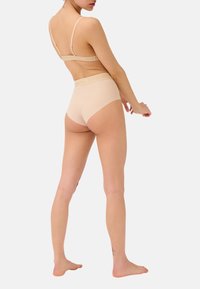 Set di biancheria intima color beige chiaro composto da un reggiseno con spalline sottili e culotte a vita alta. Realizzato in tessuto morbido, offre un design senza cuciture.
