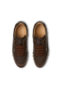 Un paio di sneaker casual marroni scuri con spesse stringhe marroni, dettagli cuciti e rivestimento interno color beige chiaro visti dall'alto.