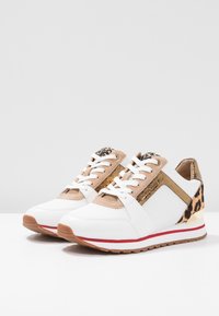 Weiße Sneakers mit goldenen Akzenten, einem Leopardenmuster an der Ferse und einer strukturierten Oberseite. Sie verfügen über weiße Schnürsenkel und eine braune Gummisohle.