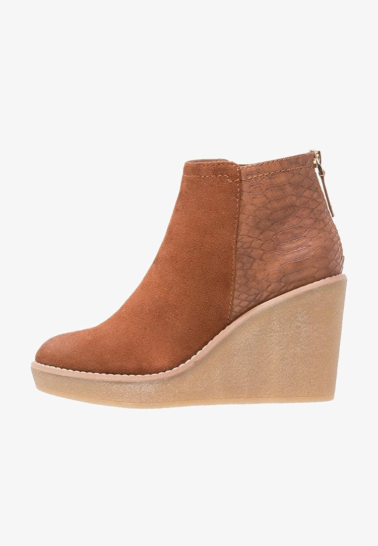 Brown wedge ankle boot with suede front, textured faux leather back, and rubber sole, featuring a rear zipper closure.