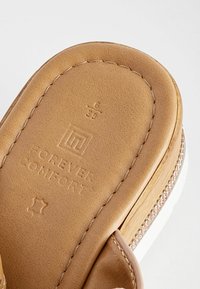 Tan synthetic leather sandal in a slide design, featuring a cushioned footbed, decorative stitching, and subtle glitter accents.