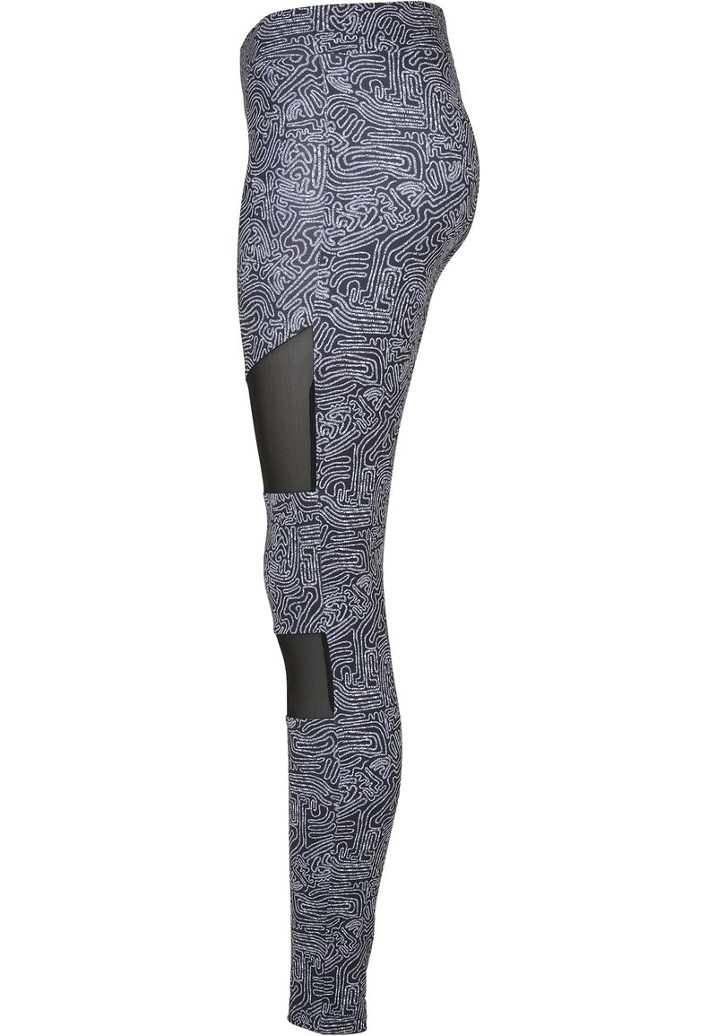 Tights med et svart og hvitt labyrintmønster, med et glatt stoff, mesh-detaljer og utklippspaneler på de nedre bena.