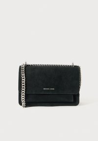 Bolso de ante negro con una cadena plateada, que presenta un cierre tipo solapa y un detalle de logo en relieve en la parte frontal. Forma compacta y rectangular.
