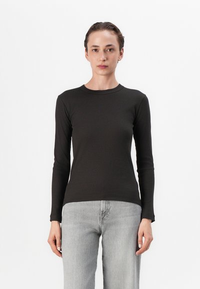 Chemise à manches longues noire côtelée avec un col rond, coupe ajustée et texture lisse, associée à un jean droit gris clair.