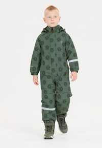 Groene waterdichte sneeuwpak met een tijgerpatroon, volledige rits, verstelbare capuchon, elastische manchetten en reflecterende accenten. Vergezeld van groene laarzen.