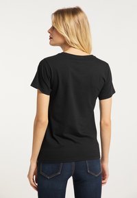 Sort bomulds T-shirt med korte ærmer, rund halsudskæring og en glat tekstur. Set fra bagfra, parret med mørkeblå jeans.
