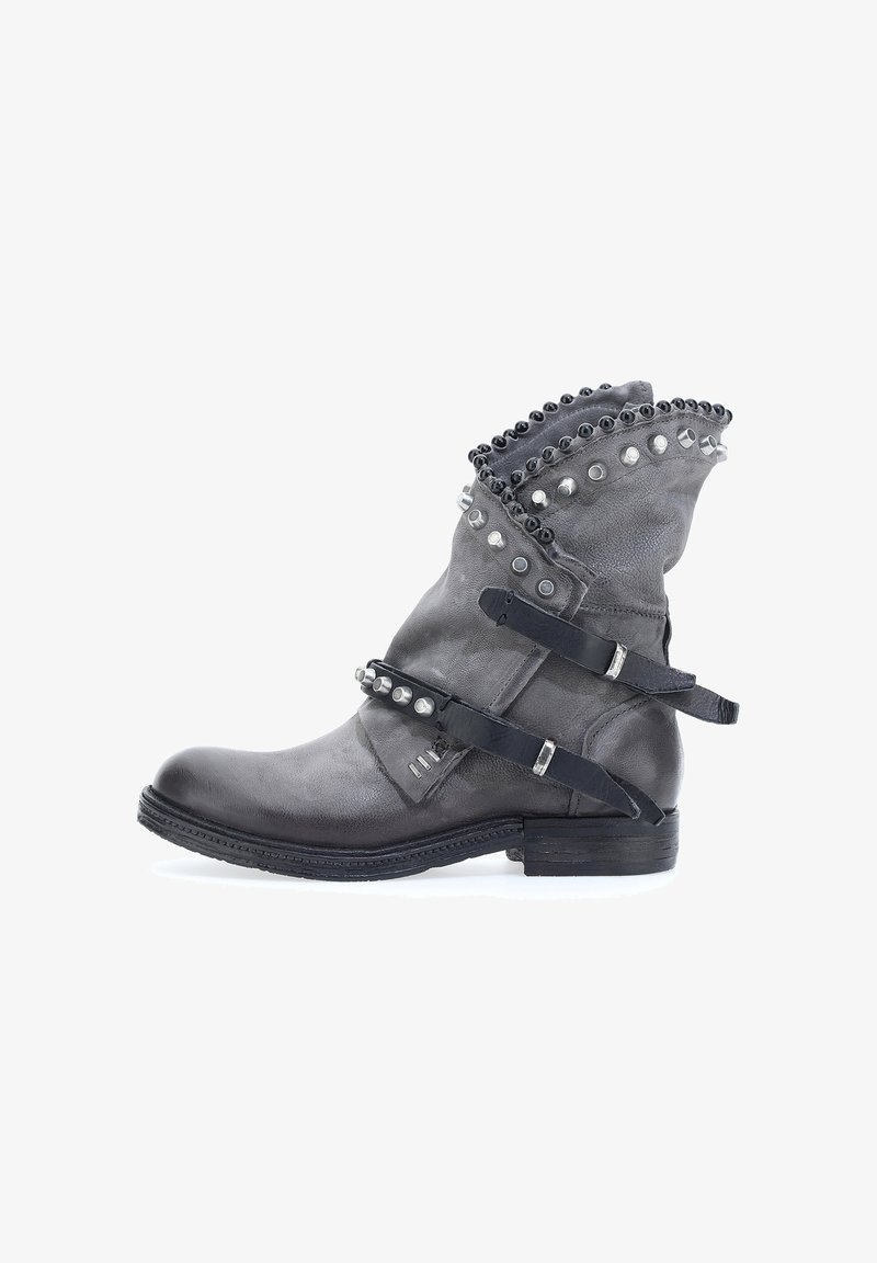 Botín de cuero gris hasta el tobillo con parte superior texturizada, tachuelas decorativas y correas. Punta redondeada y tacón apilado. Acentos a lo largo del collar.