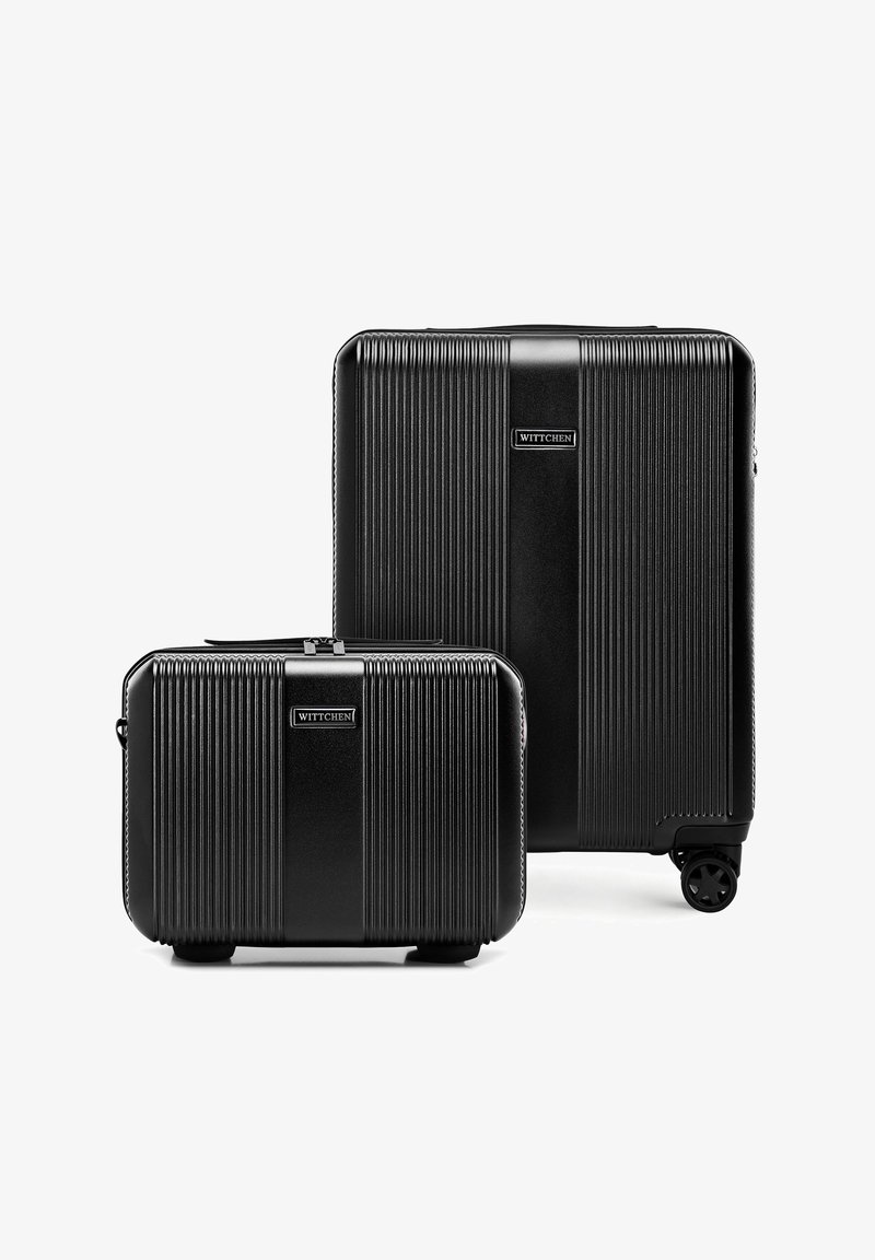 Dwie czarne, twarde walizki Wittchen z pionowymi żeberkami, jedna większa na kółkach, druga mniejsza, obie ustawione pionowo na białym tle.