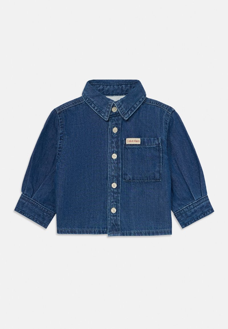 Denimskjorta i mörkblått med spetsig krage, knappstängning fram, långa ärmar och en bröstficka med en Calvin Klein-label.