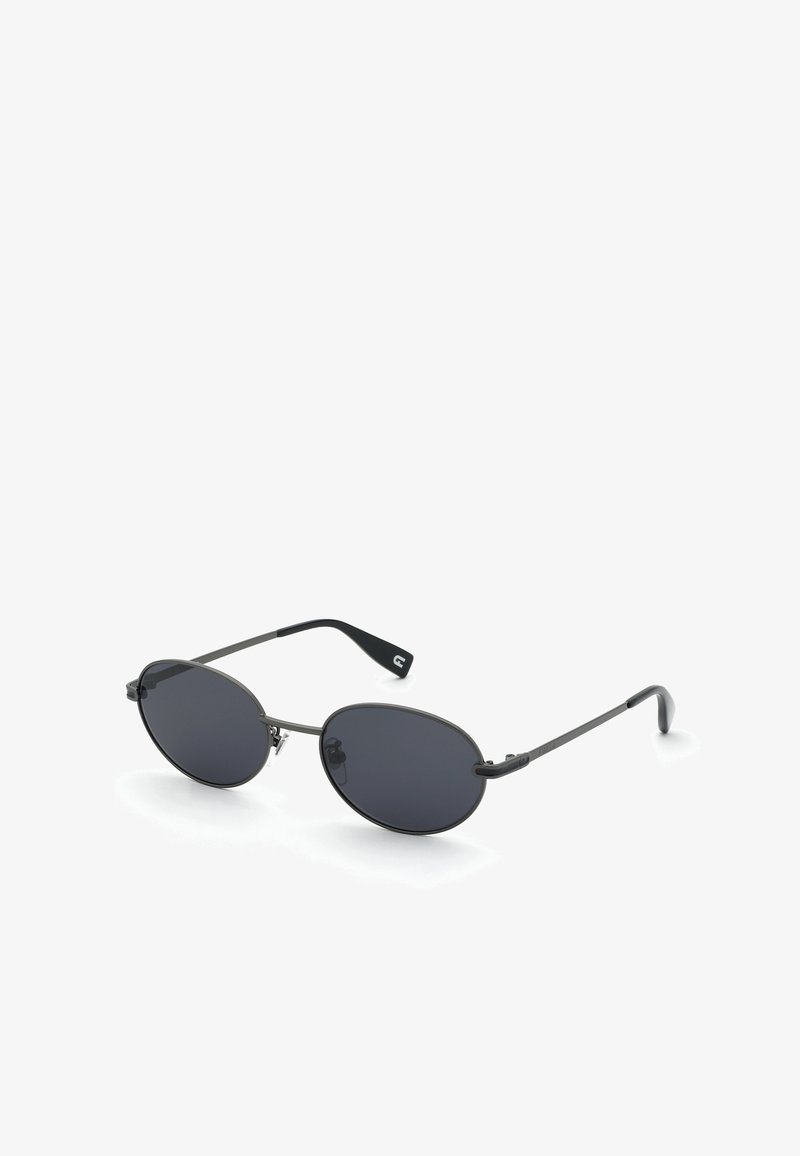 Lunettes de soleil ovales à monture métallique noire avec verres foncés et branches fines, présentées sur fond blanc.