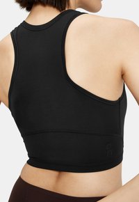 Top sport negru tip crop, cu un design racerback, realizat dintr-un material neted, având cusături minime și un logo subtil la tiv.