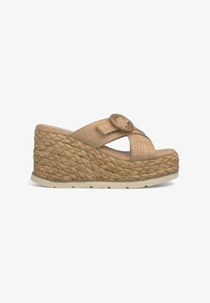 Sandale compensée avec un dessus en paille tissée et un accent circulaire. Présentant une couleur beige naturel et une semelle de style espadrille texturée.