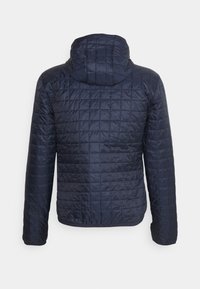 Marine gewatteerde jas met gewatteerde textuur, heeft een capuchon, lange mouwen en elastische manchetten. Glad materiaal met verzonken stikseldetails.