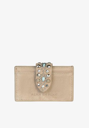 Cartera de cuero beige con superficie texturizada, que presenta una correa decorativa adornada con tachuelas metálicas y una piedra aqua en el centro.