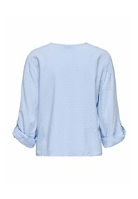Šviesiai mėlyna bliuska su tekstūrizuota taškų raštu, ilgomis rankovėmis, apvyniotomis ties riešais, apvaliu iškirpimu ir laisvu siluetu. Paprastas dizainas.
