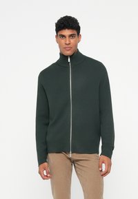 Tmavozelený zip-up sveter s vysokým golierom, rebrovanou textúrou a dlhými rukávmi. Predný zips má kovový ťahák.