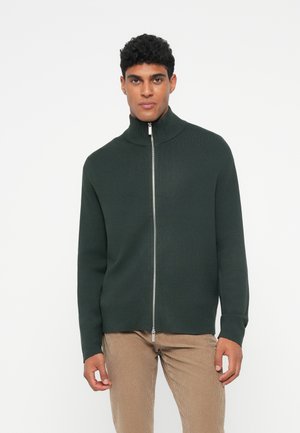 Maglione zip-up verde scuro con collo alto, texture a coste e maniche lunghe. La cerniera frontale è dotata di un tira metallico.