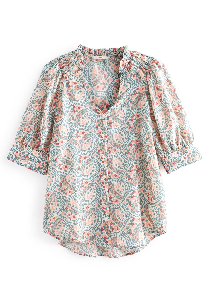 Blouse légère avec des motifs floraux et feuillages bleus, roses et pêche, manches courtes bouffantes et boutons sur le devant.