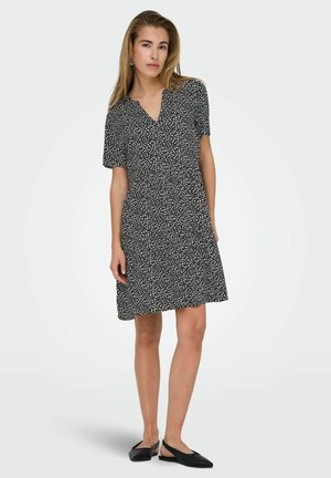 Sort kortærmet kjole med et hvidt bladmønster, v-udskæring og en flydende form. Sæt sammen med sorte slingback-sko.