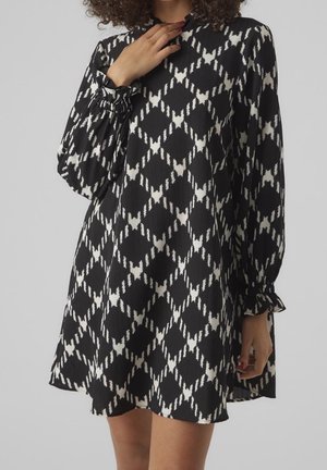 Abito a motivi in bianco e nero con un design a diamante, maniche lunghe con polsini arricciati e un collo alto realizzato in tessuto strutturato.